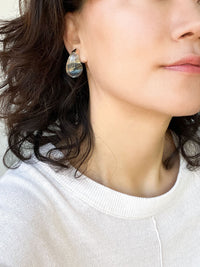 A pair of clear resin teardrop-shaped stud earrings with gold-toned caps, showcasing their smooth, glossy finish and minimalist design.