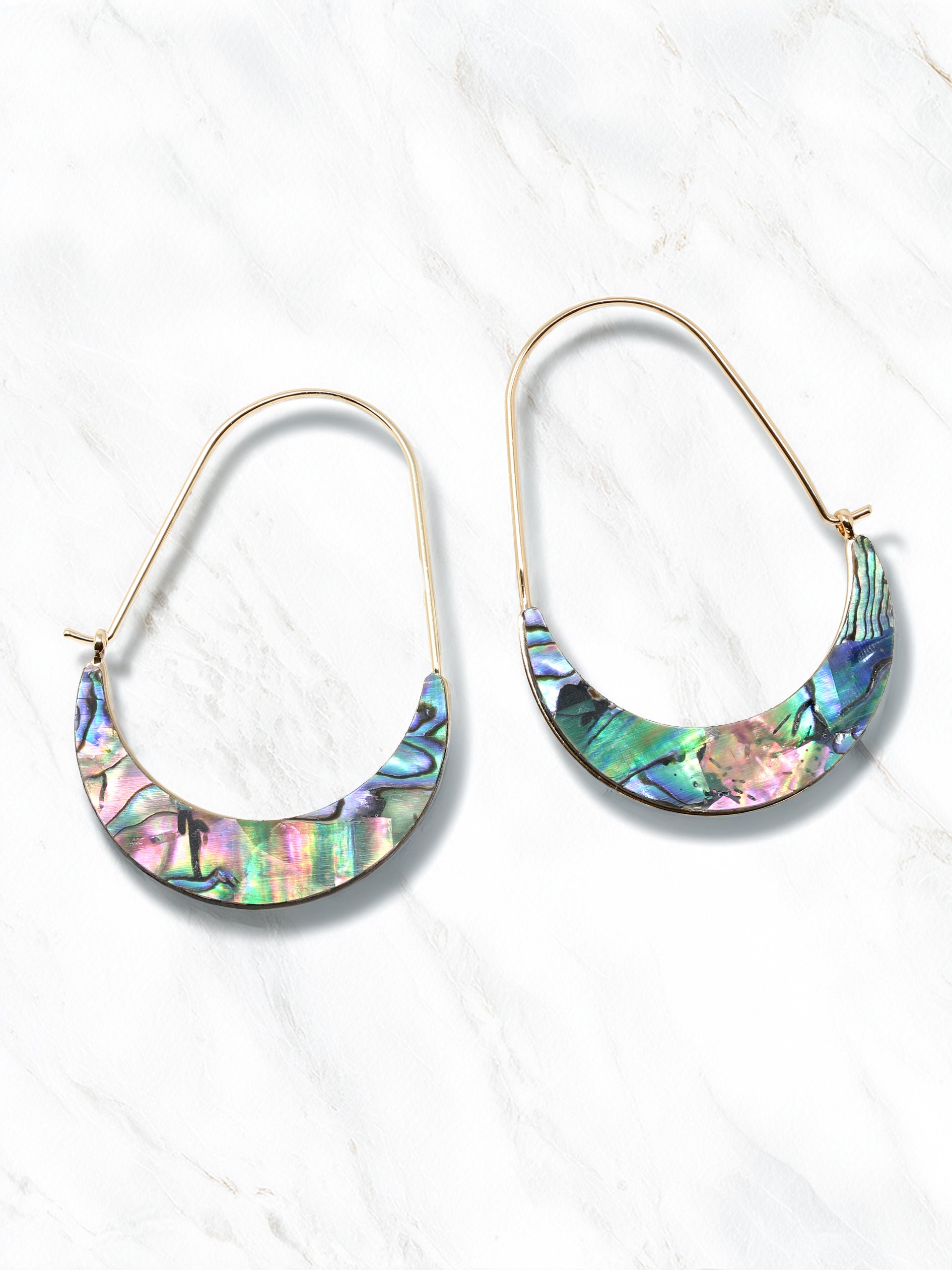 A pair of crescent-shaped hoop earrings featuring iridescent abalone shell inlays with vibrant shades of green, blue, purple, and pink. The earrings are set on delicate gold-tone wire hoops.