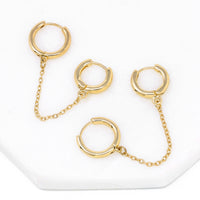 Modern loop earplug earrings in gold, connected with chains.
