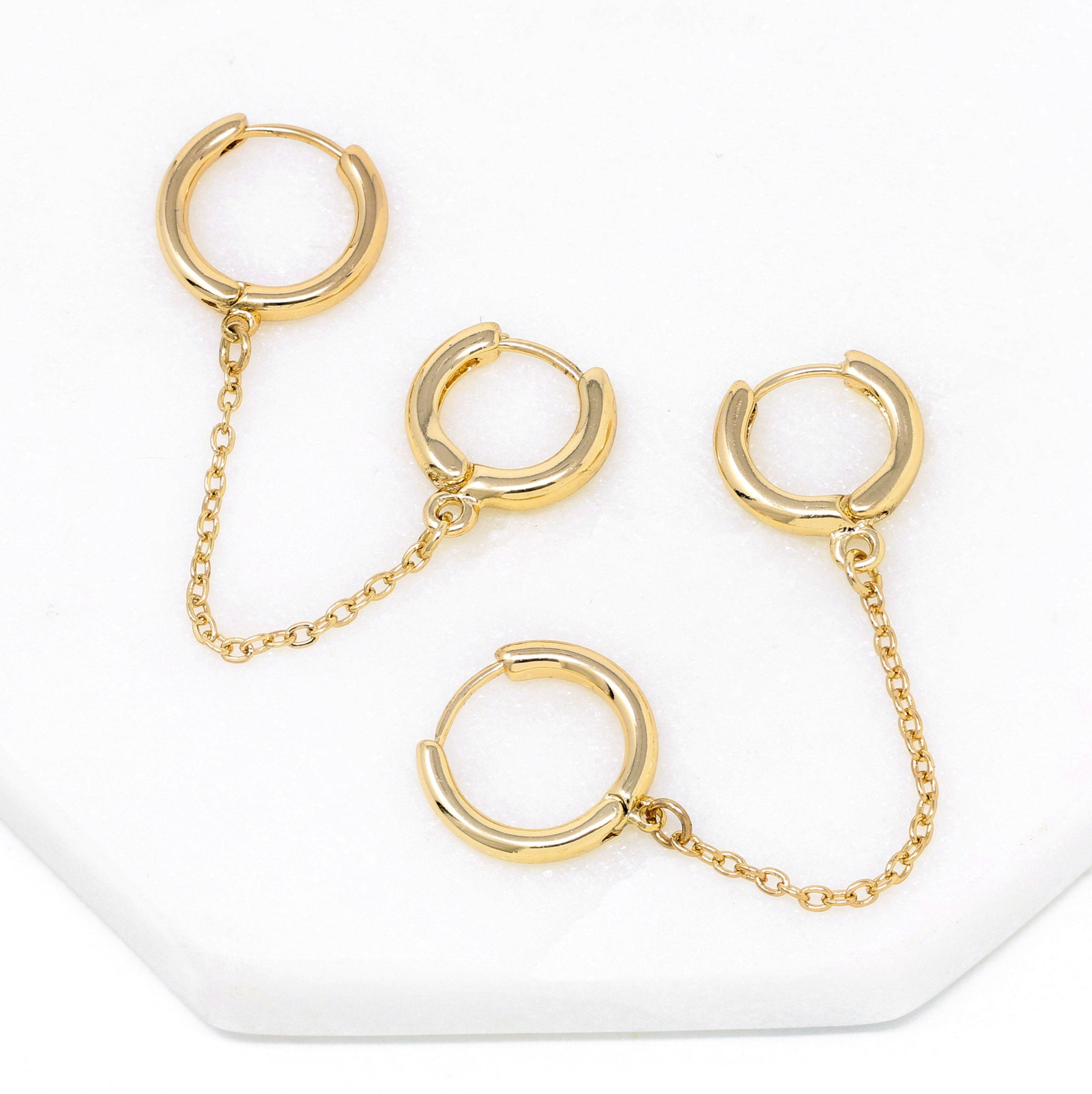 Modern loop earplug earrings in gold, connected with chains.