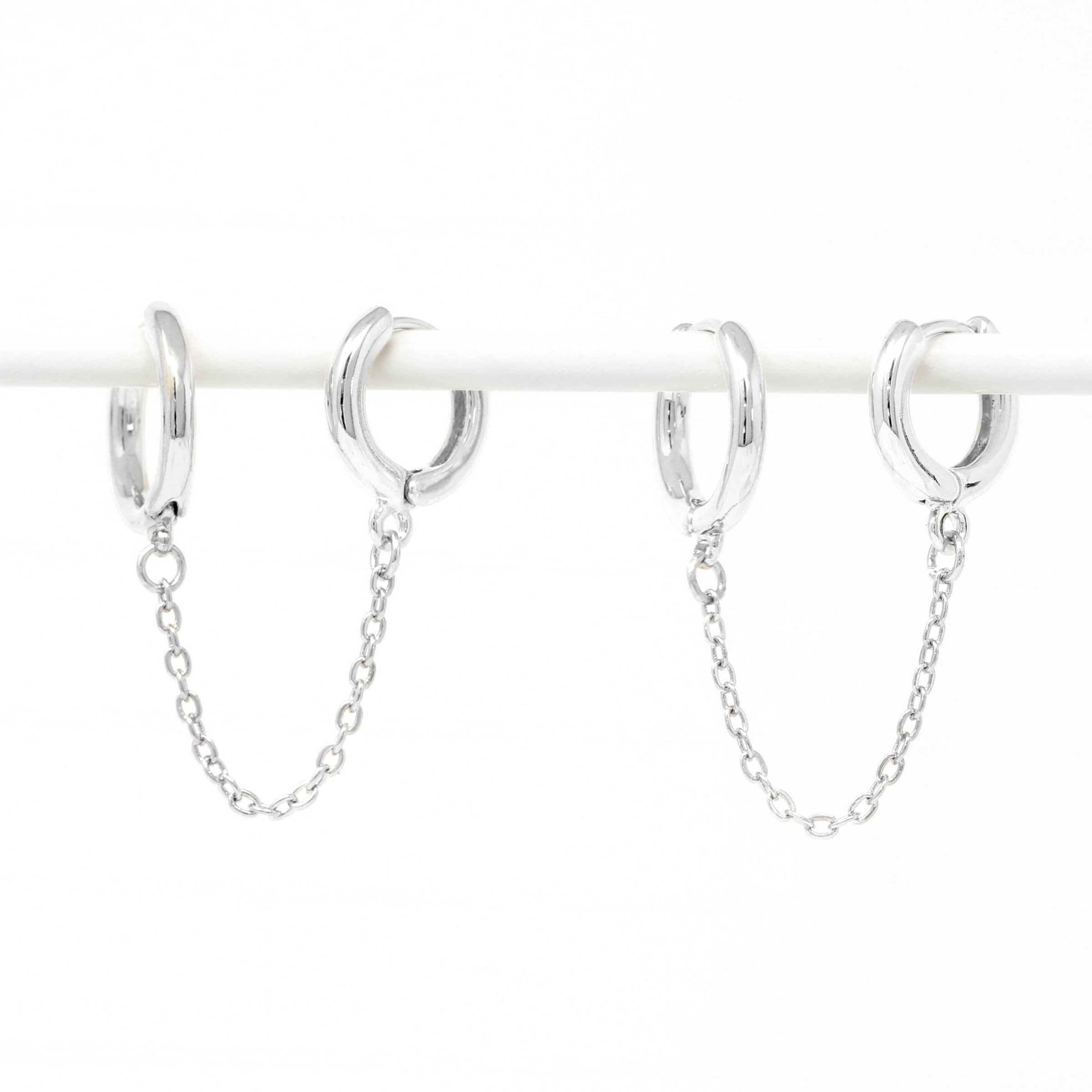 Modern loop earplug earrings in silver, connected with chains.
