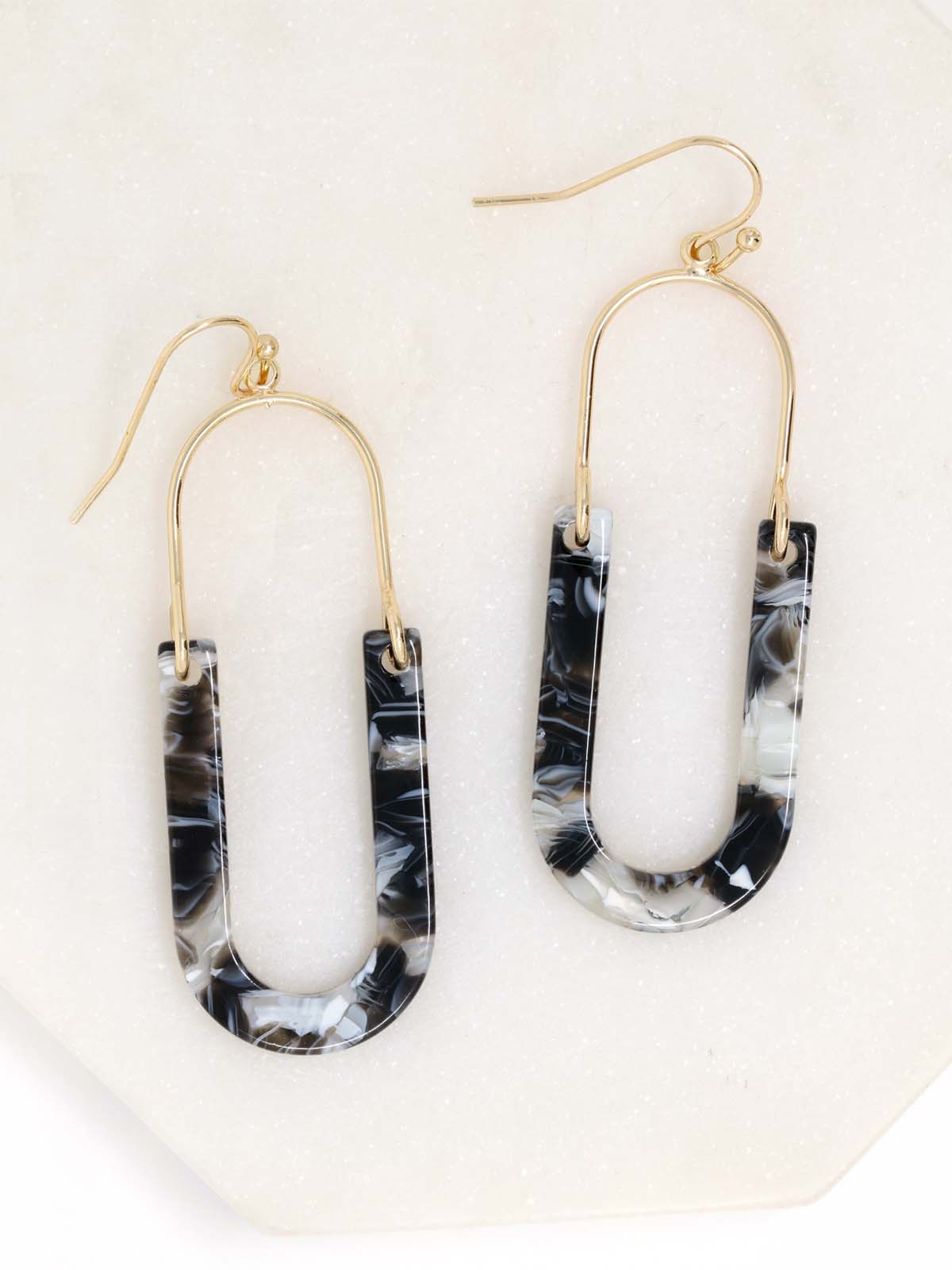 A pair of oval resin drop and dangle earrings with gold-tone hooks and frames. The U-shaped resin pendants feature a black tone.
