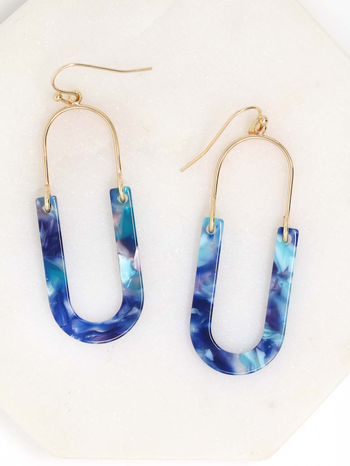 A pair of oval resin drop and dangle earrings with gold-tone hooks and frames. The U-shaped resin pendants feature a blue tone.