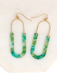 A pair of oval resin drop and dangle earrings with gold-tone hooks and frames. The U-shaped resin pendants feature a green tone.