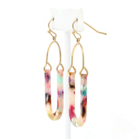An image of a pair of resin earrings featuring multi-colored drops suspended from gold-plated hooks. The resin drops are a blend of vibrant hues, including pink, blue, green, and purple, creating a playful and eye-catching effect.
