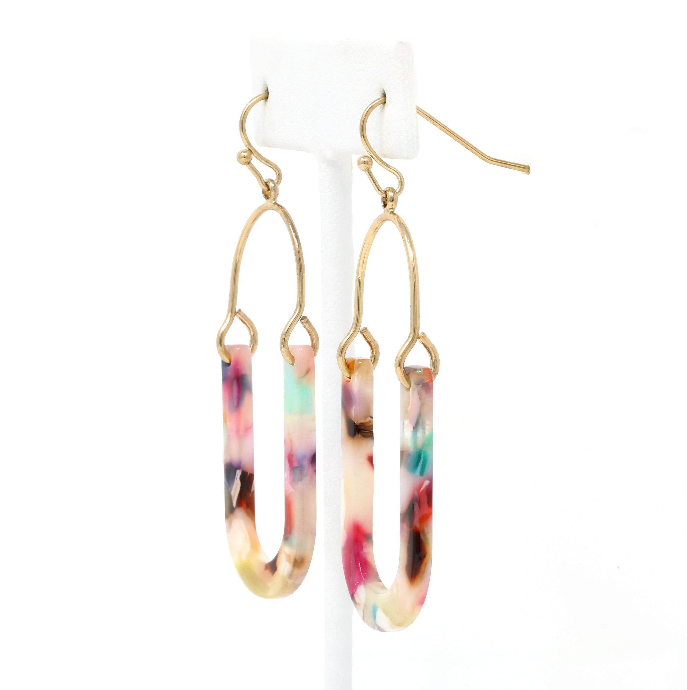 An image of a pair of resin earrings featuring multi-colored drops suspended from gold-plated hooks. The resin drops are a blend of vibrant hues, including pink, blue, green, and purple, creating a playful and eye-catching effect.