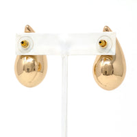 A close-up of gold puffy teardrop hollow bold earrings, showcasing their modern and minimalist design. The earrings make a statement with their sleek metal construction and distinctive shape.