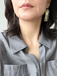 A pair of geometric statement earrings featuring natural mother of pearl shell with an iridescent finish, set in a sleek, modern design.