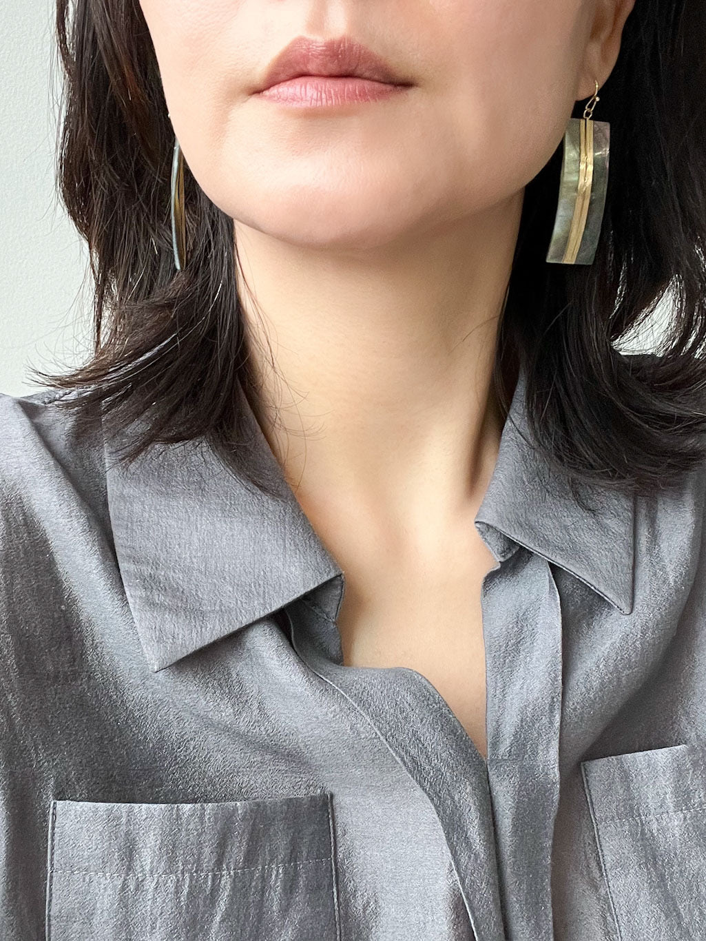 A pair of geometric statement earrings featuring natural mother of pearl shell with an iridescent finish, set in a sleek, modern design.