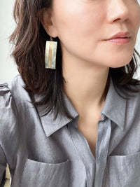 A pair of geometric statement earrings featuring natural mother of pearl shell with an iridescent finish, set in a sleek, modern design.