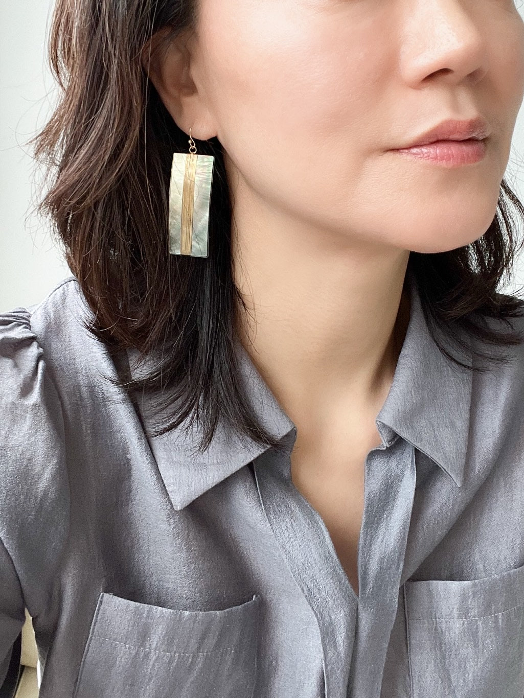 A pair of geometric statement earrings featuring natural mother of pearl shell with an iridescent finish, set in a sleek, modern design.