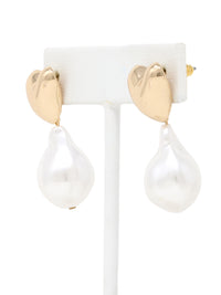 A pair of elegant earrings featuring polished gold-tone puffy heart studs with dangling irregular baroque pearls. The earrings are displayed on a white jewelry stand against a clean background, showcasing their modern yet timeless design.