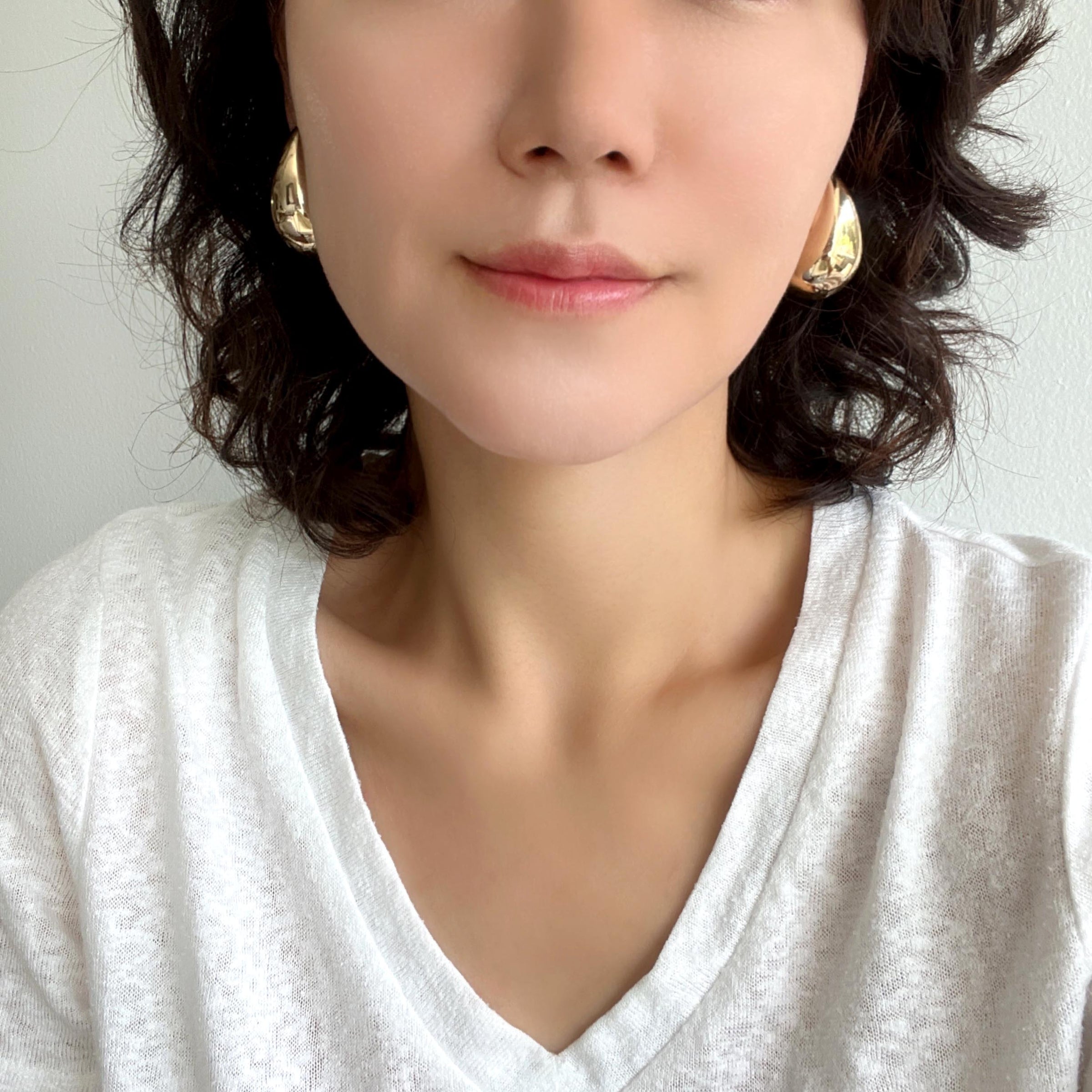 A close-up of gold puffy teardrop hollow bold earrings, showcasing their modern and minimalist design. The earrings make a statement with their sleek metal construction and distinctive shape.