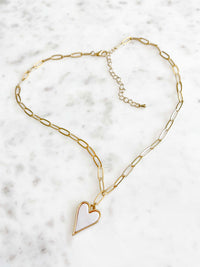A heart-shaped charm gold necklace featuring Mother of Pearl shell encrustation, suspended on a paperclip chain.