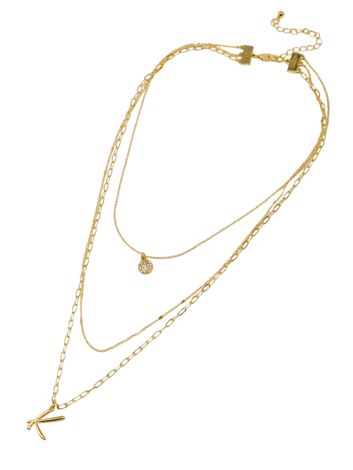 A three-layered gold necklace featuring a script initial charm and a small circle charm paved with stones.