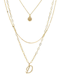 A three-layered gold necklace featuring a script initial charm and a small circle charm paved with stones.