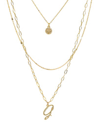 A three-layered gold necklace featuring a script initial charm and a small circle charm paved with stones.
