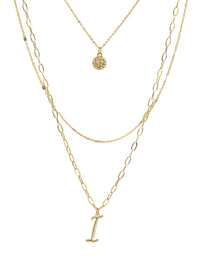 A three-layered gold necklace featuring a script initial charm and a small circle charm paved with stones.