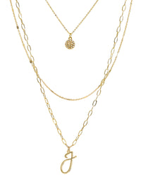 A three-layered gold necklace featuring a script initial charm and a small circle charm paved with stones.