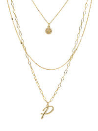 A three-layered gold necklace featuring a script initial charm and a small circle charm paved with stones.