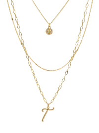 A three-layered gold necklace featuring a script initial charm and a small circle charm paved with stones.