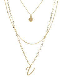 A three-layered gold necklace featuring a script initial charm and a small circle charm paved with stones.