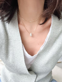 Gold double-layered necklace with a puffy crystal-paved teardrop charm, featuring a snake chain and a paperclip chain design.