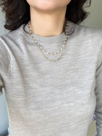 An elegant double-layered pearl necklace featuring a sophisticated paperclip chain in a radiant gold finish, combining classic pearls with modern design for a timeless and stylish accessory.
