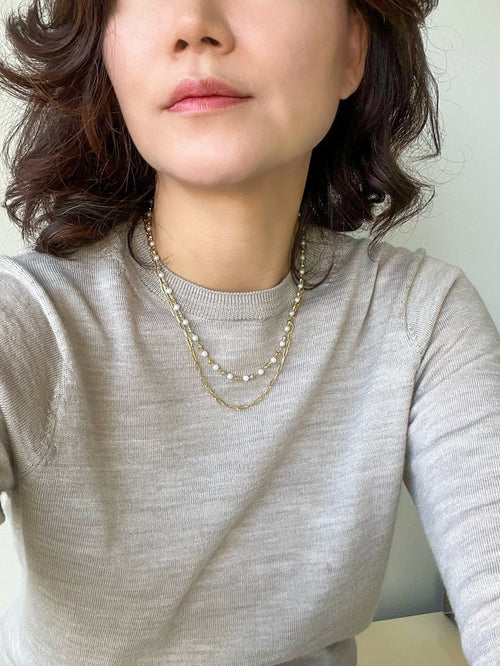 An elegant double-layered pearl necklace featuring a sophisticated paperclip chain in a radiant gold finish, combining classic pearls with modern design for a timeless and stylish accessory.