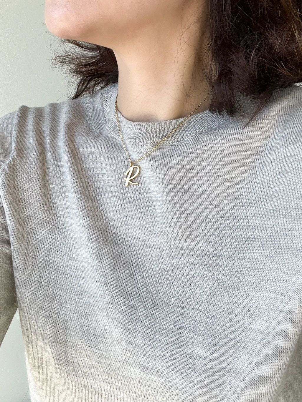 Script initial letter charm necklace dangled in a gold-filled paperclip chain.