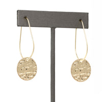 Lightweight metal hoop earrings in gold with small hammered circle charms.