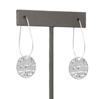 Lightweight metal hoop earrings in silver with small hammered circle charms.