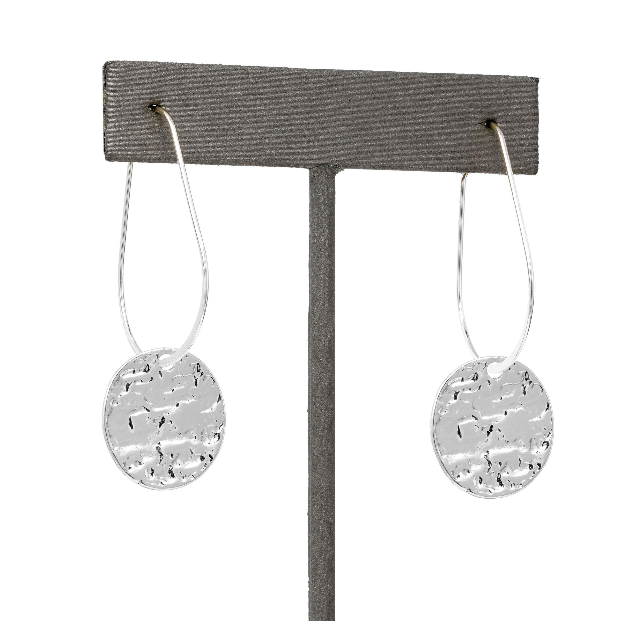Lightweight metal hoop earrings in silver with small hammered circle charms.