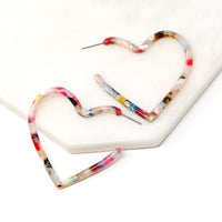Two heart shaped hoop earrings with a white base and multi-colored swirls of red, pink, blue, yellow, green, and brown.