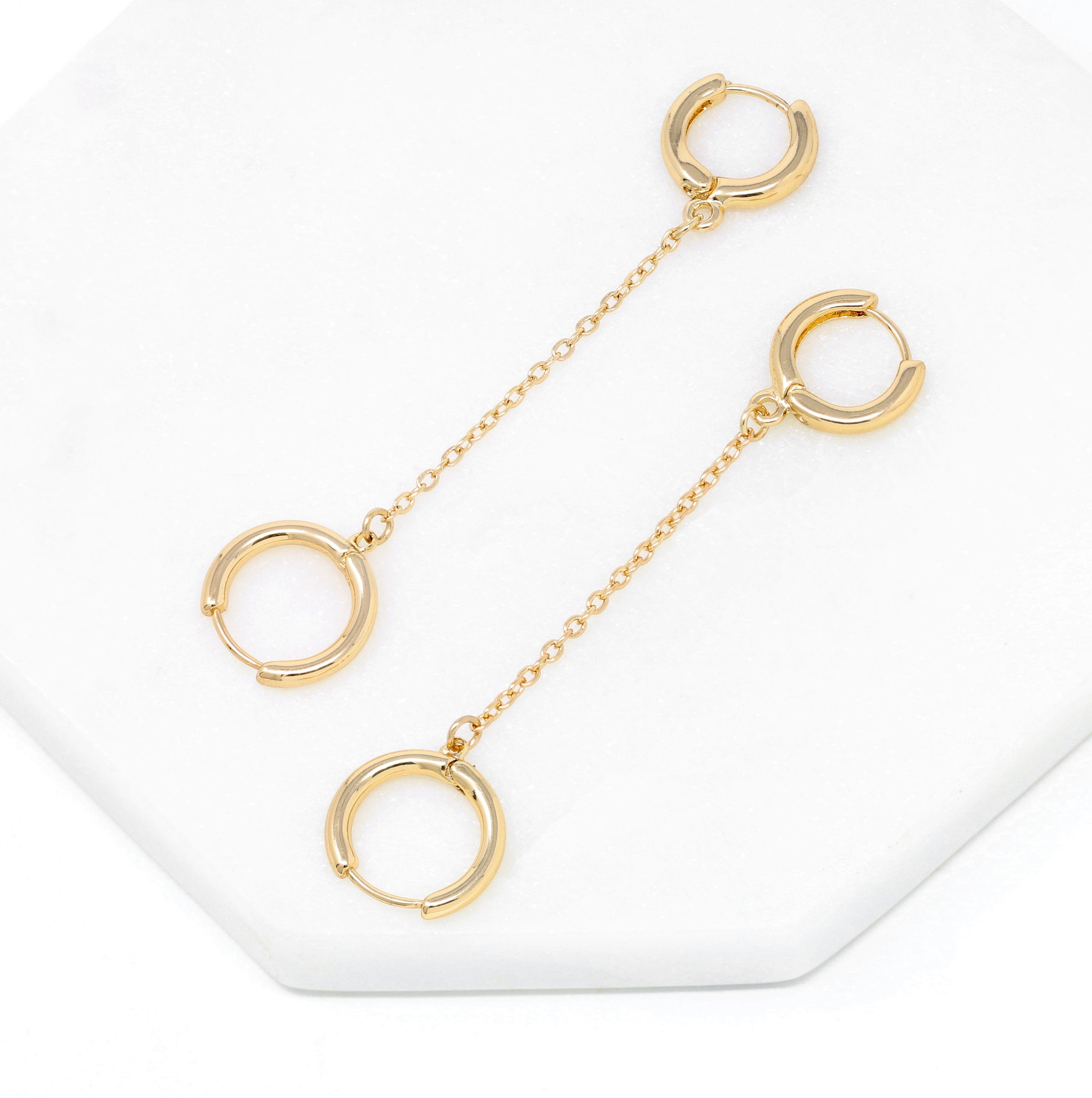 Modern loop earplug earrings in gold, connected with chains.