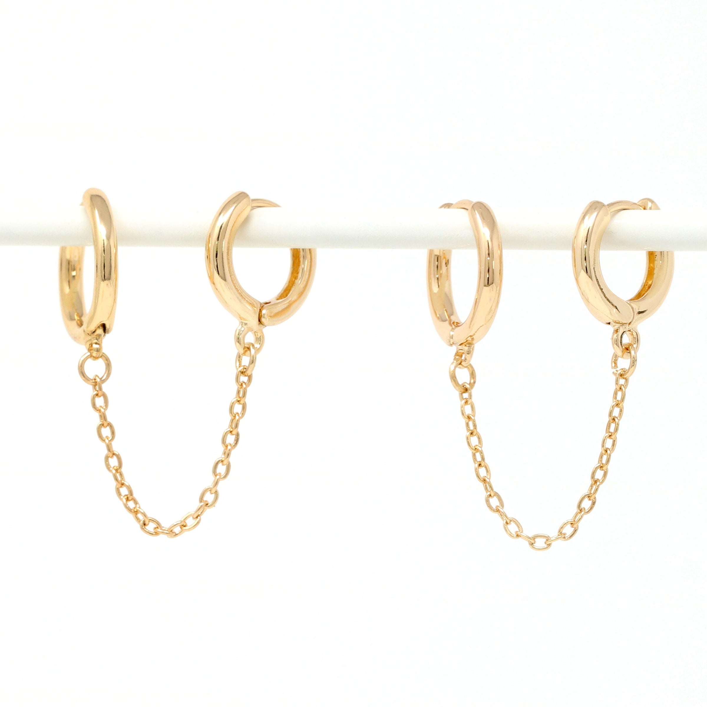 Modern loop earplug earrings in gold, connected with chains.