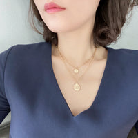 Wearing a two-layered paperclip chain necklace in gold dangled with two small charms.