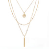 A set of triple layered necklace in gold with a small smiley face and a skinny bar charms.