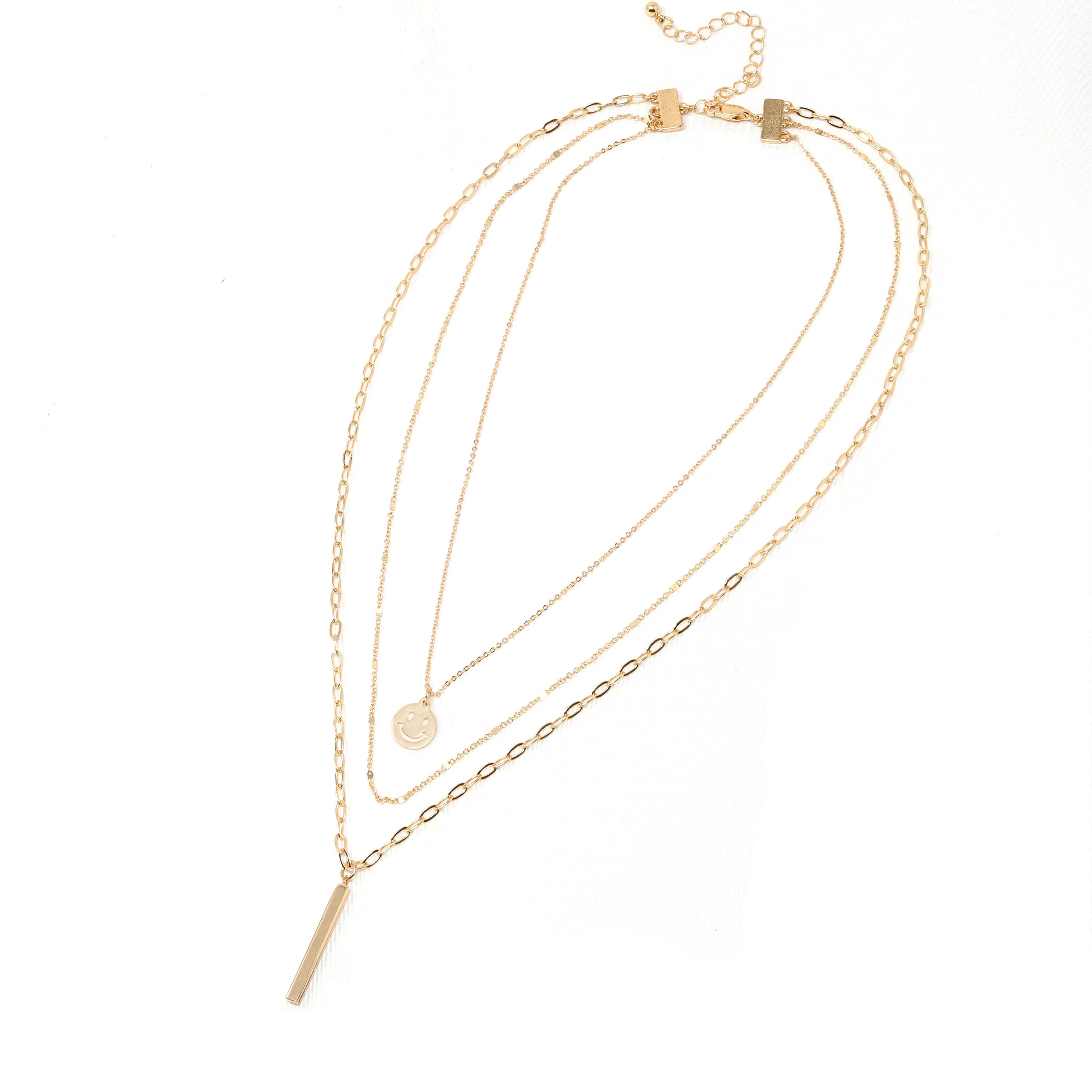 A set of triple layered necklace in gold with a small smiley face and a skinny bar charms.