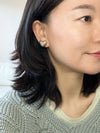 A pair of gold-tone textured puffy heart stud earrings with a delicate, intricate surface pattern.