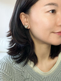 A pair of gold-tone textured puffy heart stud earrings with a delicate, intricate surface pattern.