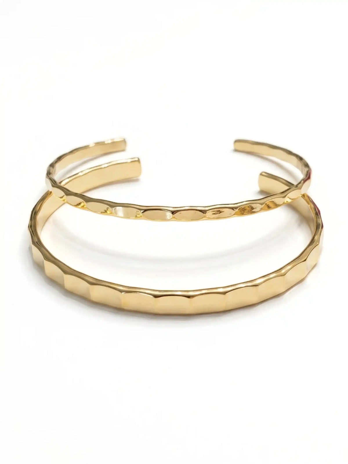 Two overlapping gold-tone cuff bracelets with a textured, scalloped hammered finish, displayed on a clean white background.