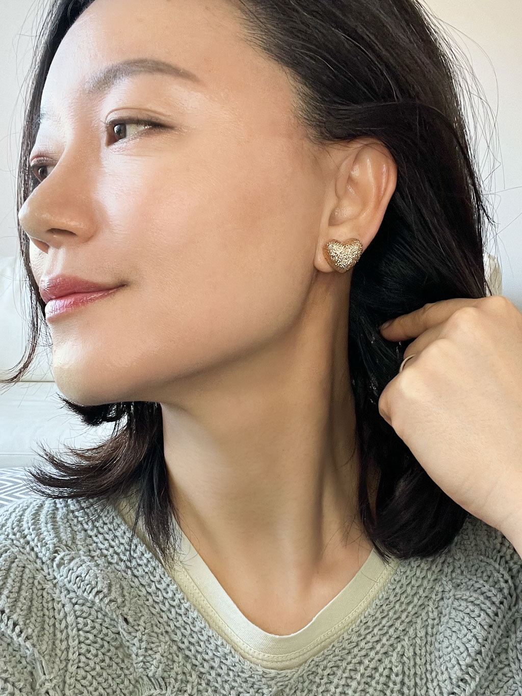 A pair of gold-tone textured puffy heart stud earrings with a delicate, intricate surface pattern.
