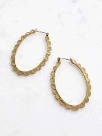Two gold-colored oval hoop earrings with a scalloped edge design. The earrings are displayed on a white surface. The earrings have a simple hook closure.