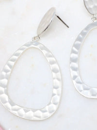 Silver earrings with teardrop-shaped white stones on a light background