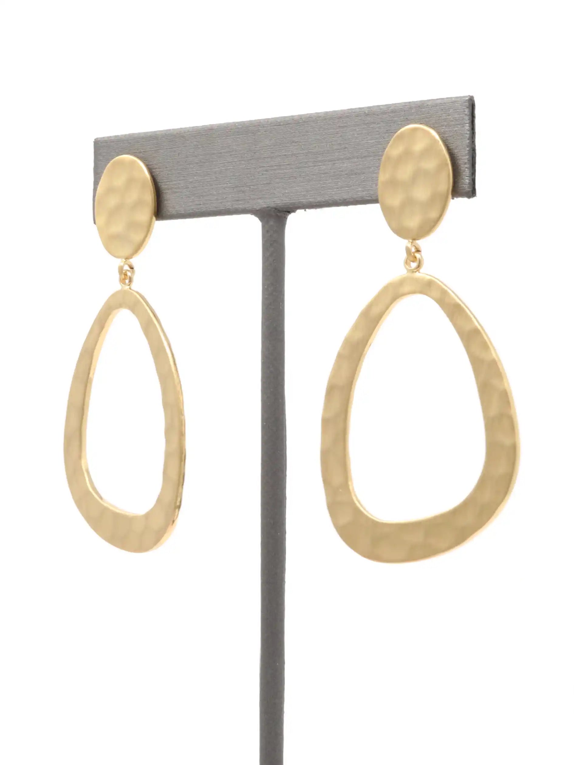 Gold hoop earrings on a gray stand against a white background