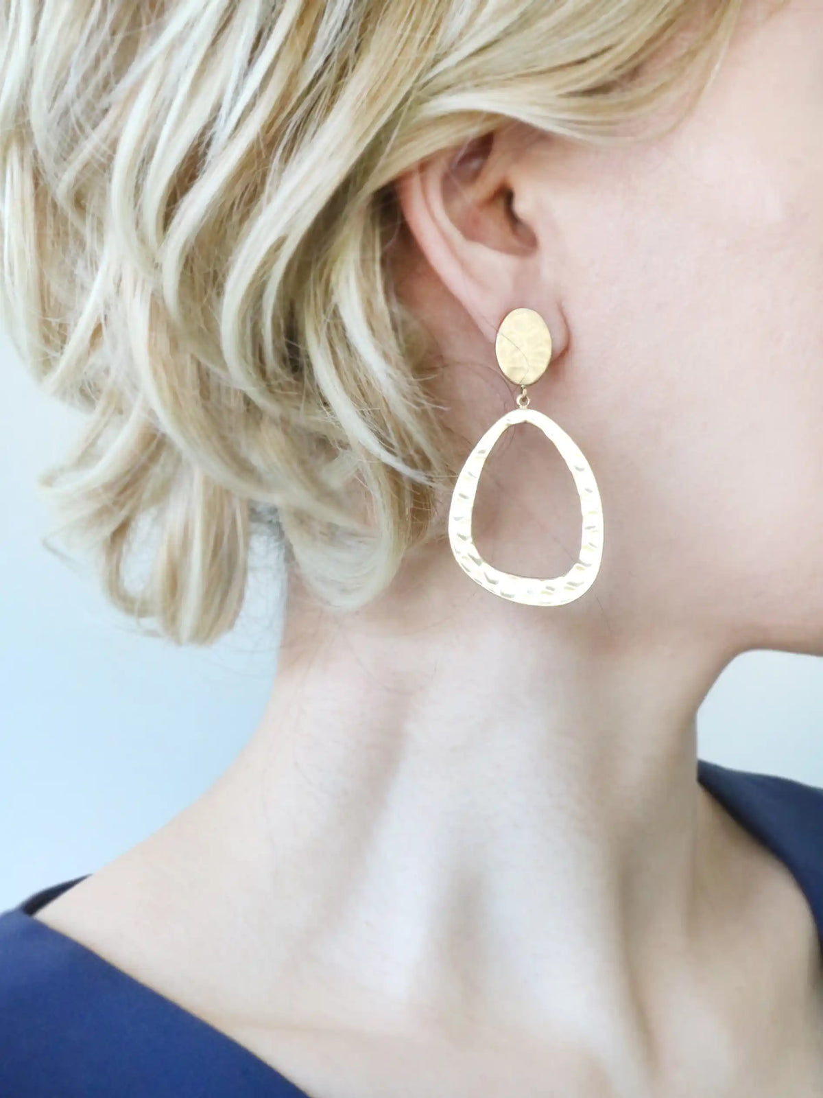 Gold hoop earrings worn by a person with blonde hair.