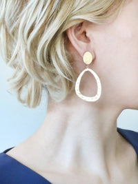 Gold hoop earrings worn by a person with blonde hair.
