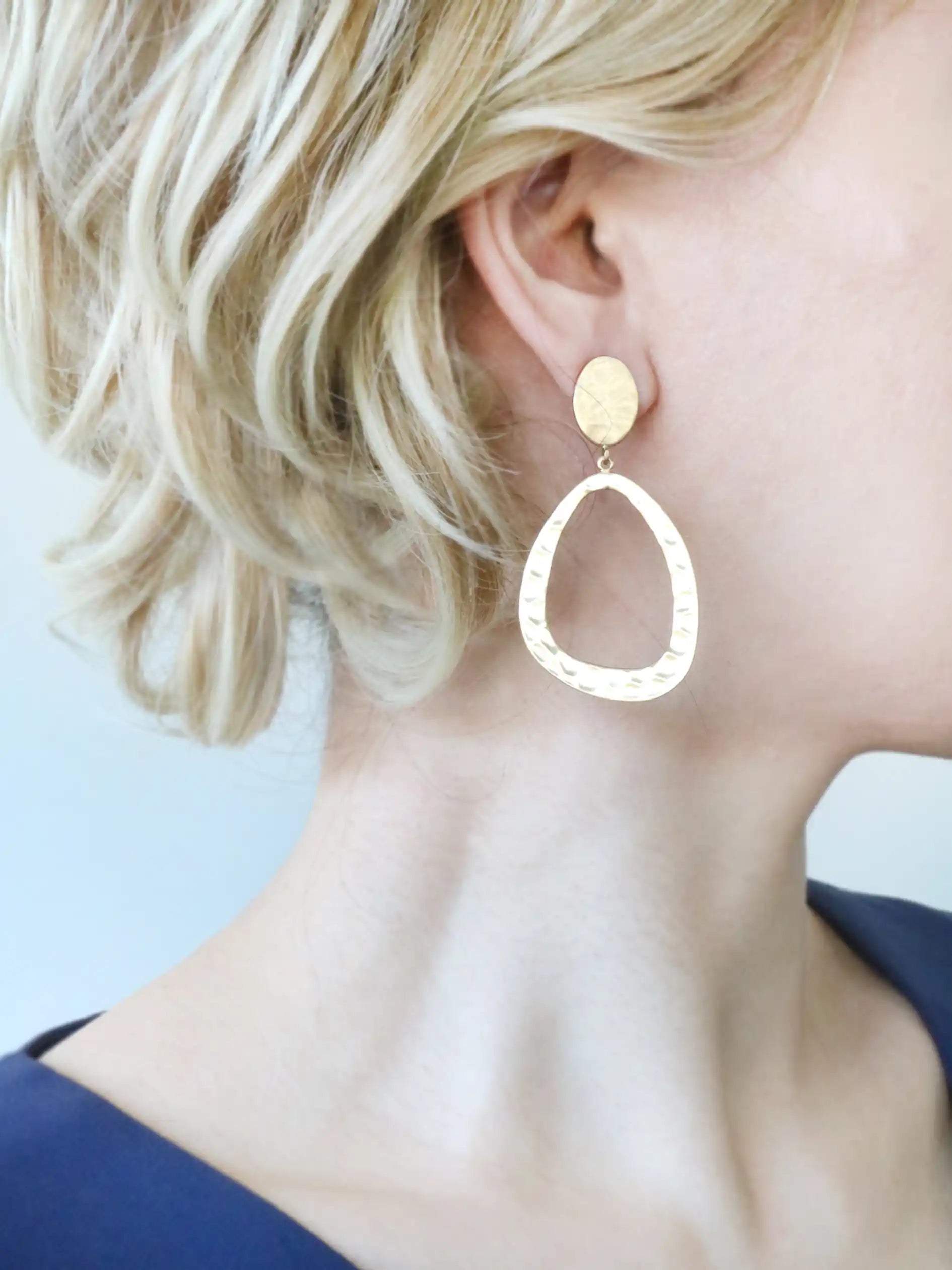 Gold hoop earrings worn by a person with blonde hair.