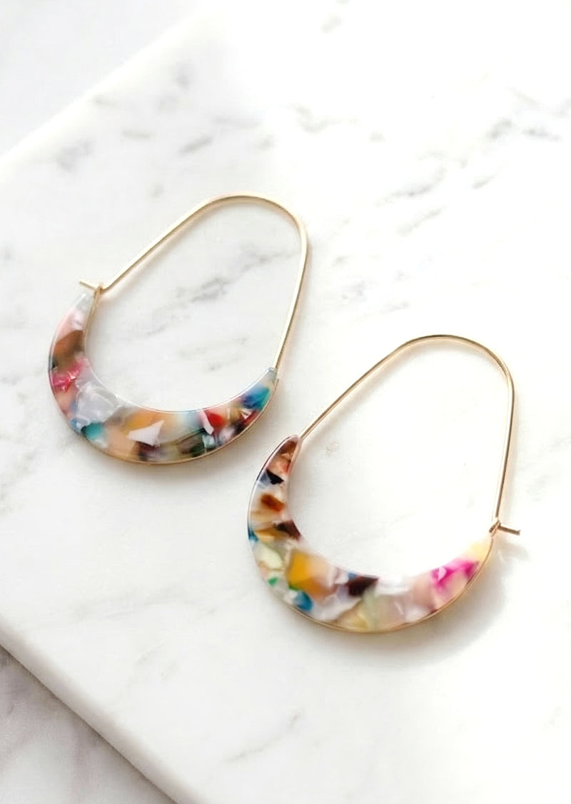 Colorful hoop earrings on a marble surface.